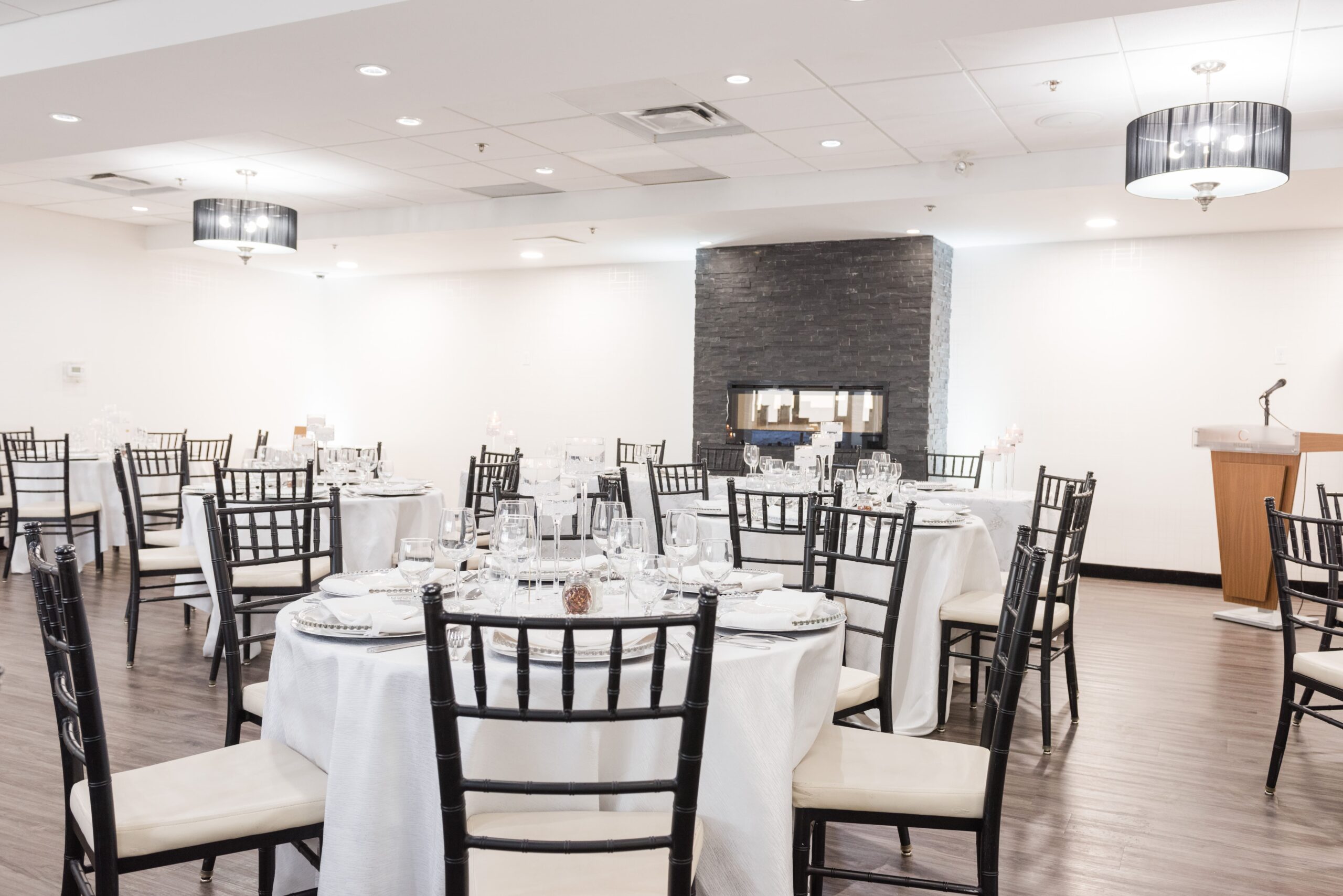 A modern banquet hall set for a wedding event with arranged tables, chairs, and dinnerware.