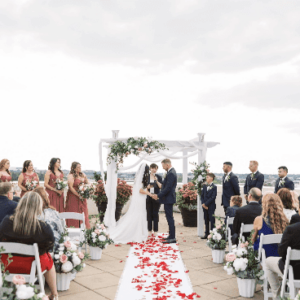 A wedding ceremony with the couple standing at the altar, surrounded by attendants and guests.