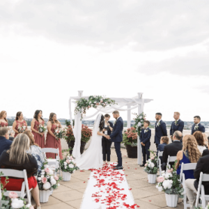 Outdoor weddings ceremony with a couple at the altar, surrounded by guests and floral decorations.