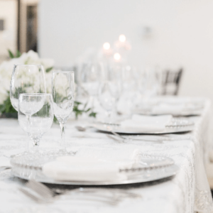 An elegantly set table with glassware, plates, and floral arrangements, ready for a wedding.