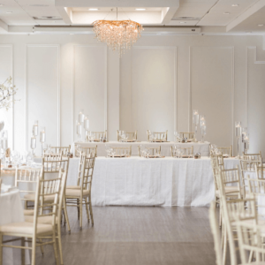 Elegant banquet hall set up with tables, chairs, and a chandelier for formal weddings.