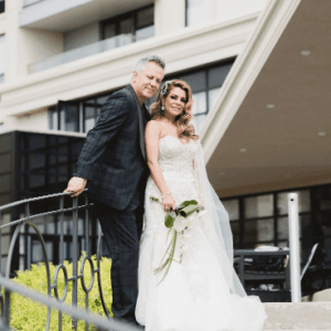 A couple in wedding attire posing on a staircase.