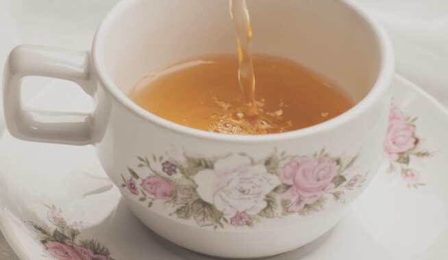 Tea being poured into a floral porcelain cup at a wedding.