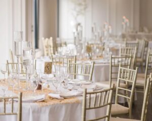 Elegant wedding banquet hall setup with decorated tables and gold chiavari chairs.