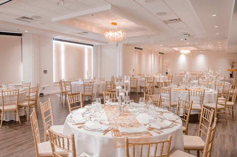 Elegant banquet hall set up for a formal event with arranged tables, chairs, and dinnerware.