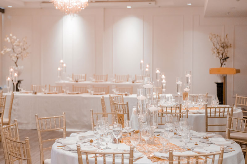 Elegant banquet hall set up for a formal event with decorated tables and ambient lighting.