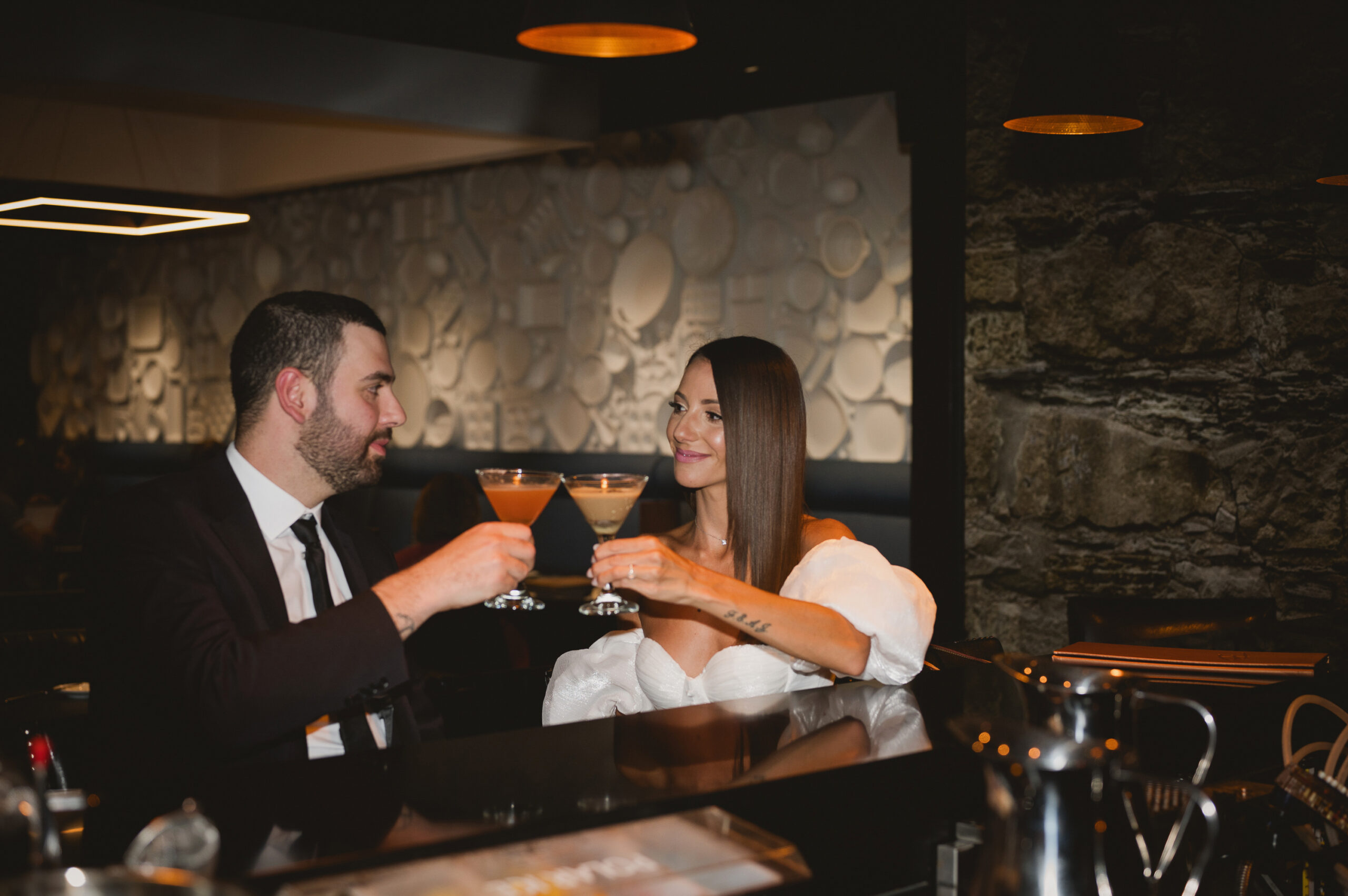 A couple toasting with cocktails at an elegant bar.