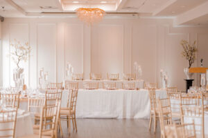 Elegant banquet hall prepared for an event, with set tables and chairs and soft, warm lighting.