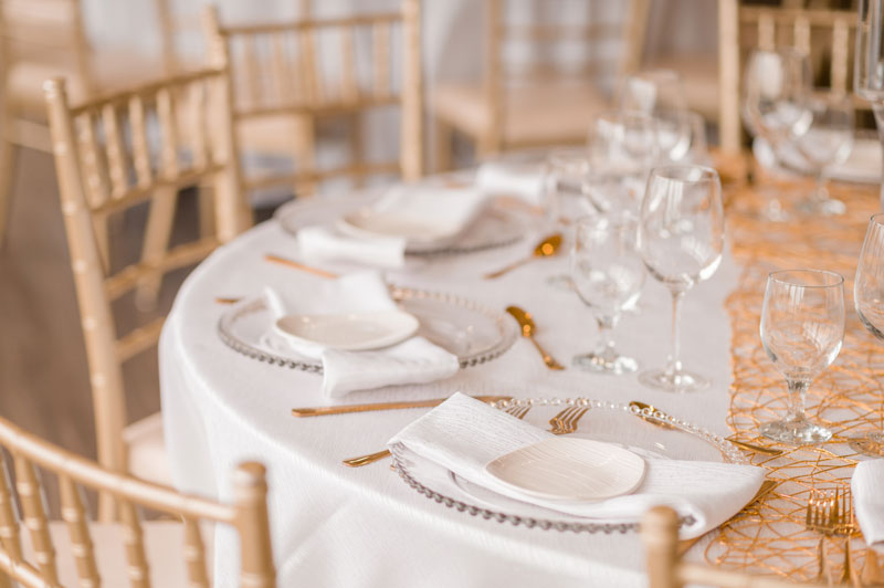 Elegant table setting with glassware and golden chairs for a formal event.